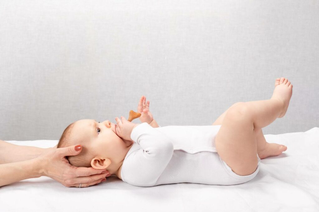 image montrant un bébé sur une table d'examen avec les mains d'une ostéopathe
