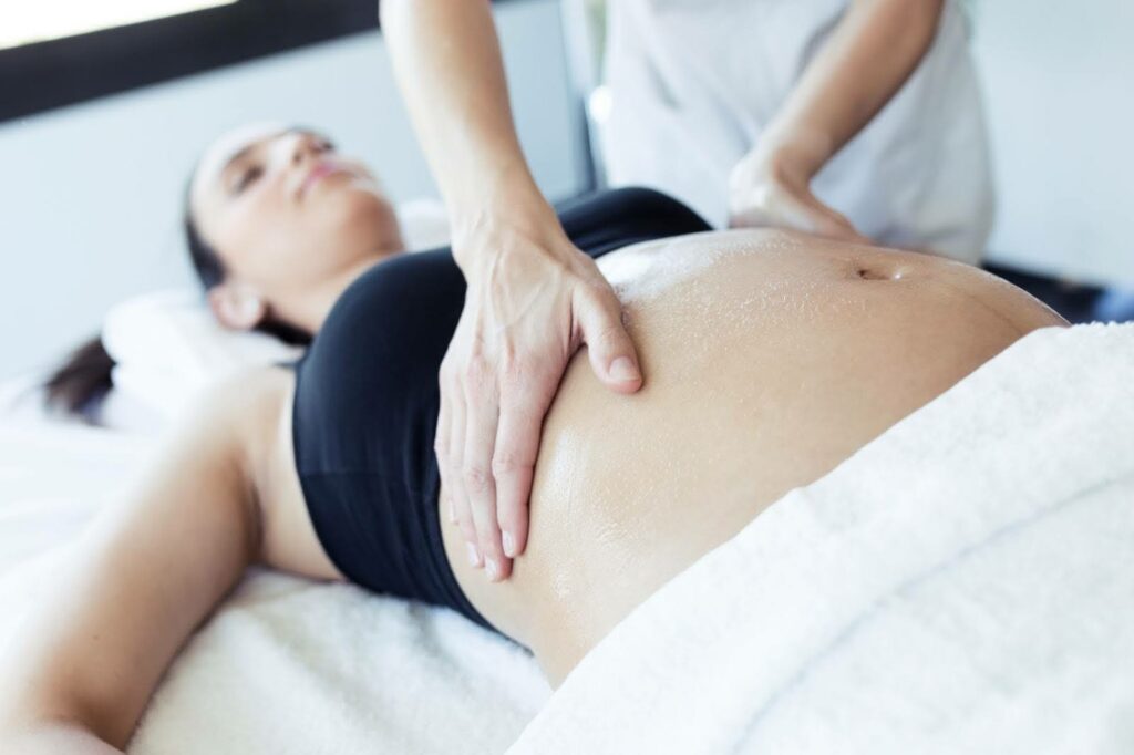 Image montrant une ostéopathe en train d'examiner le ventre d'une femme enceinte